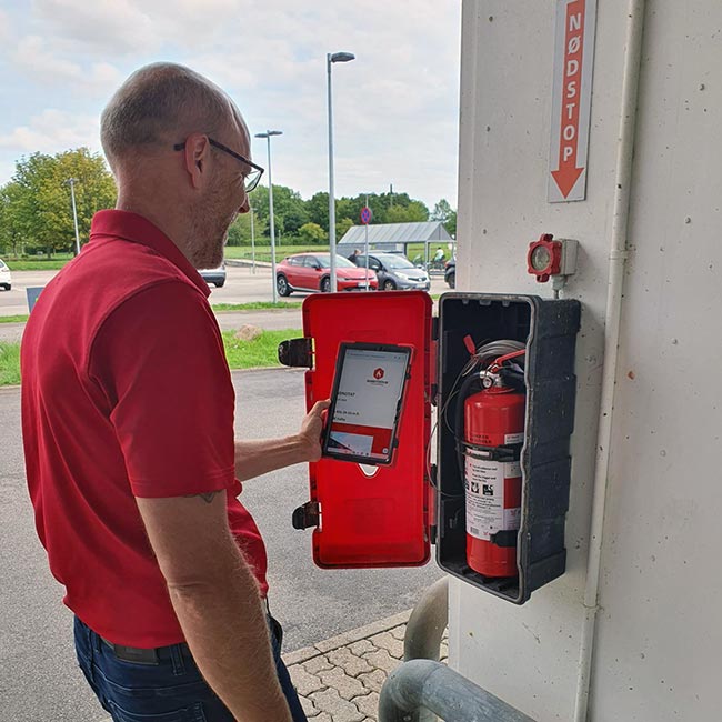 Person tjekker brandmateriel for fejl og mangler